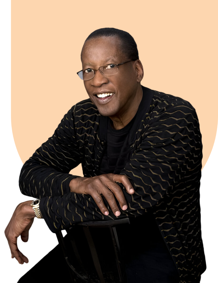 Smiling man wearing glasses and patterned jacket.